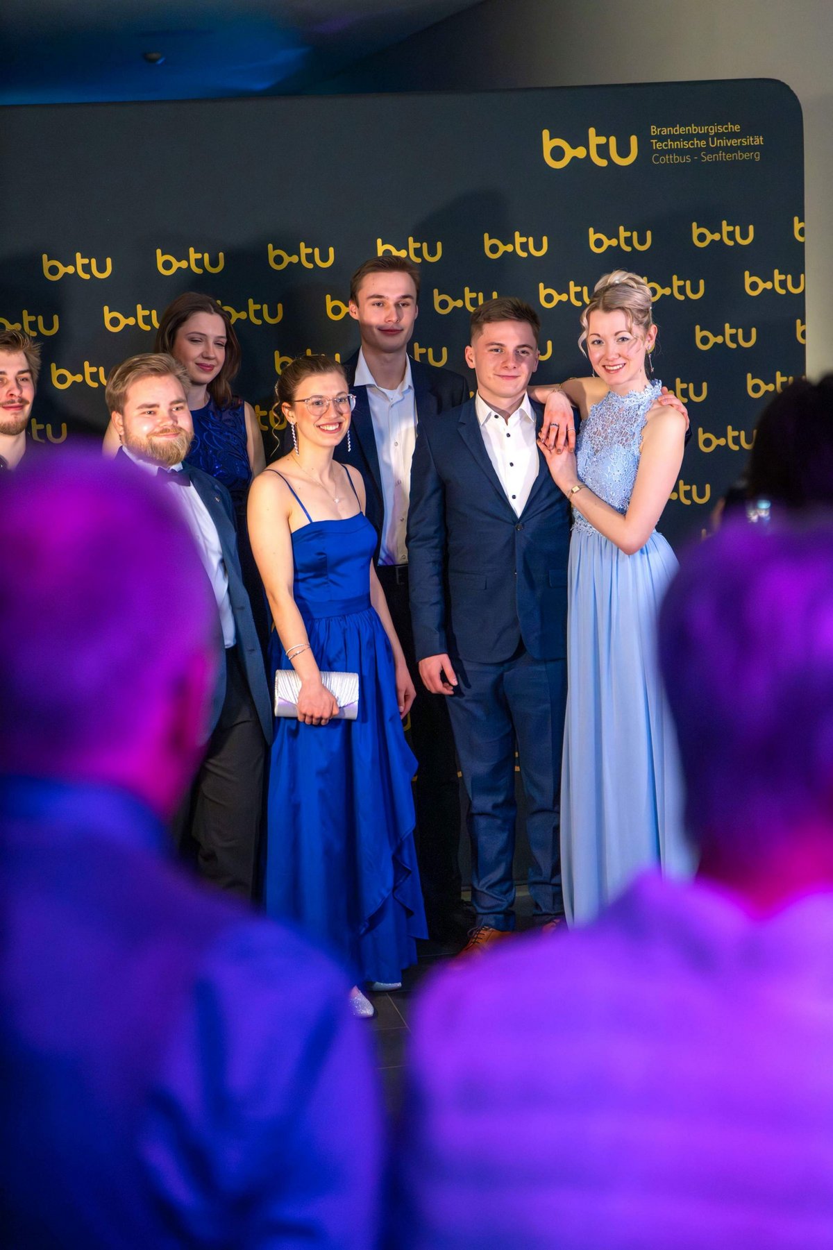 A group of ball guests in front of the BTU photo wall.