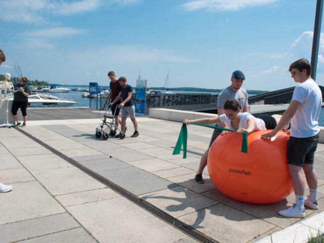 Das Foto zeigt Studierende der Physiotherapie, die Übungen am Seehafen Senftenberg demonstrieren. 