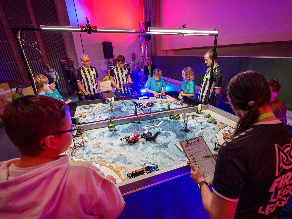 Schülerteam steuern an den Spieltischen der FIRST LEGO LEAGUE ihre Roboter.