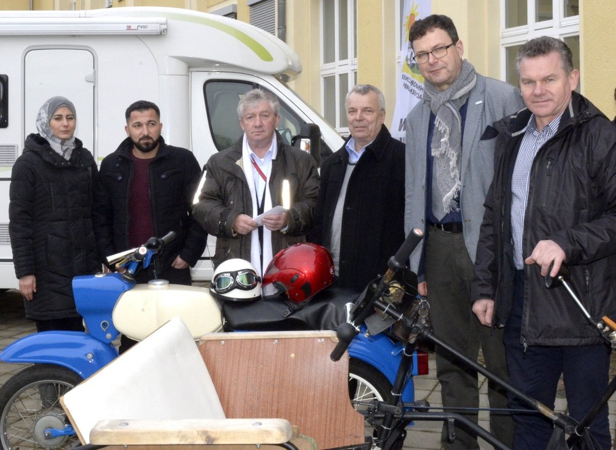 Partner des Projektes International zum Thema Elektromobilität und Interessierte stehen am Laborgebäude Maschinenbau hinter Mopeds mit Elektroantrieben.