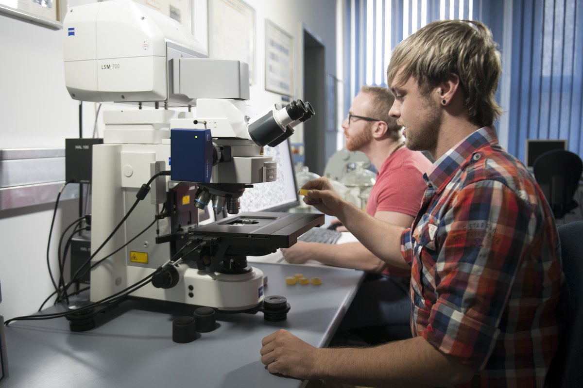 Studierende an einem Miskroskop im Labaor für die Werkstoffprüfung