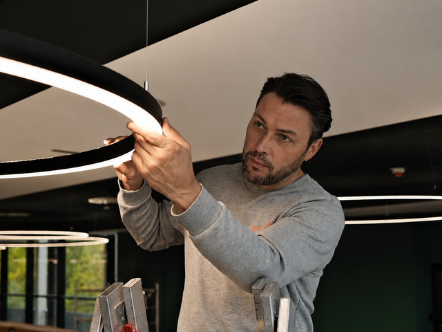 Stefan Restemeier (leuchtstoff*) bei der Installation seiner Leuchten in der Mensa. Foto: leuchtstoff