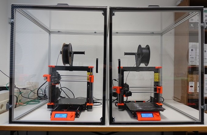 Foto von zwei FDM 3D-Drucker Prusa i3 MK3 mit orangenen Bauteilen