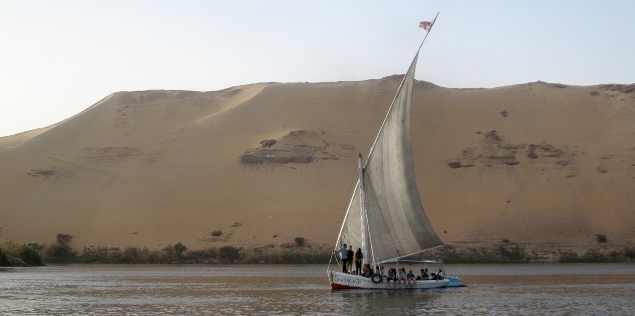 Ein Segelboot mit Studierenden im Master Heritage Conservation and Site Management segelt vor einer Sanddüne entlang