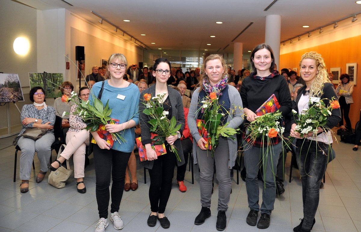 Studierende mit Blumen bei der Ausstellungseröffnung.