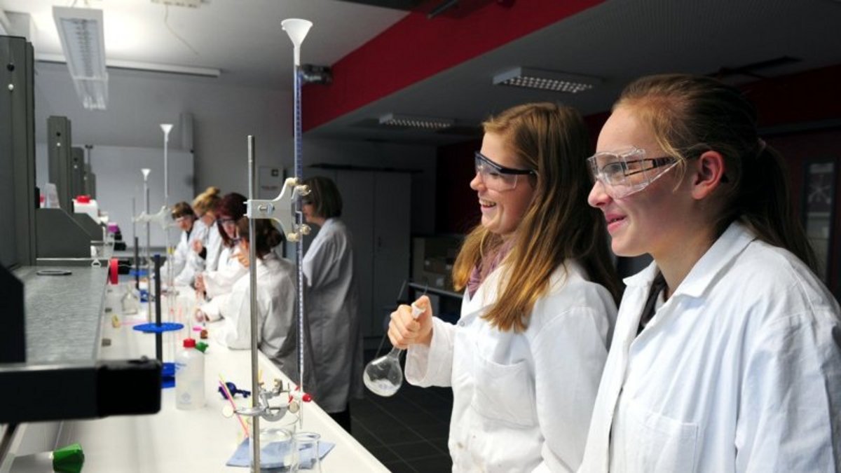 Schülerinnen in Kittel und mit Schutzbrille im Unex Schülerlabor