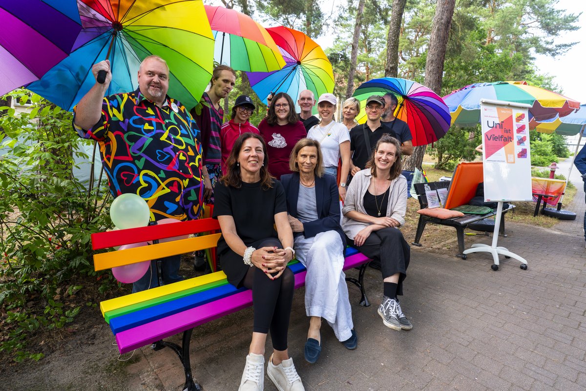 Gruppe mit Cottbuser Bürgermeisterin und BTU-Präsidentin sitzend auf der Regenbogenbank n