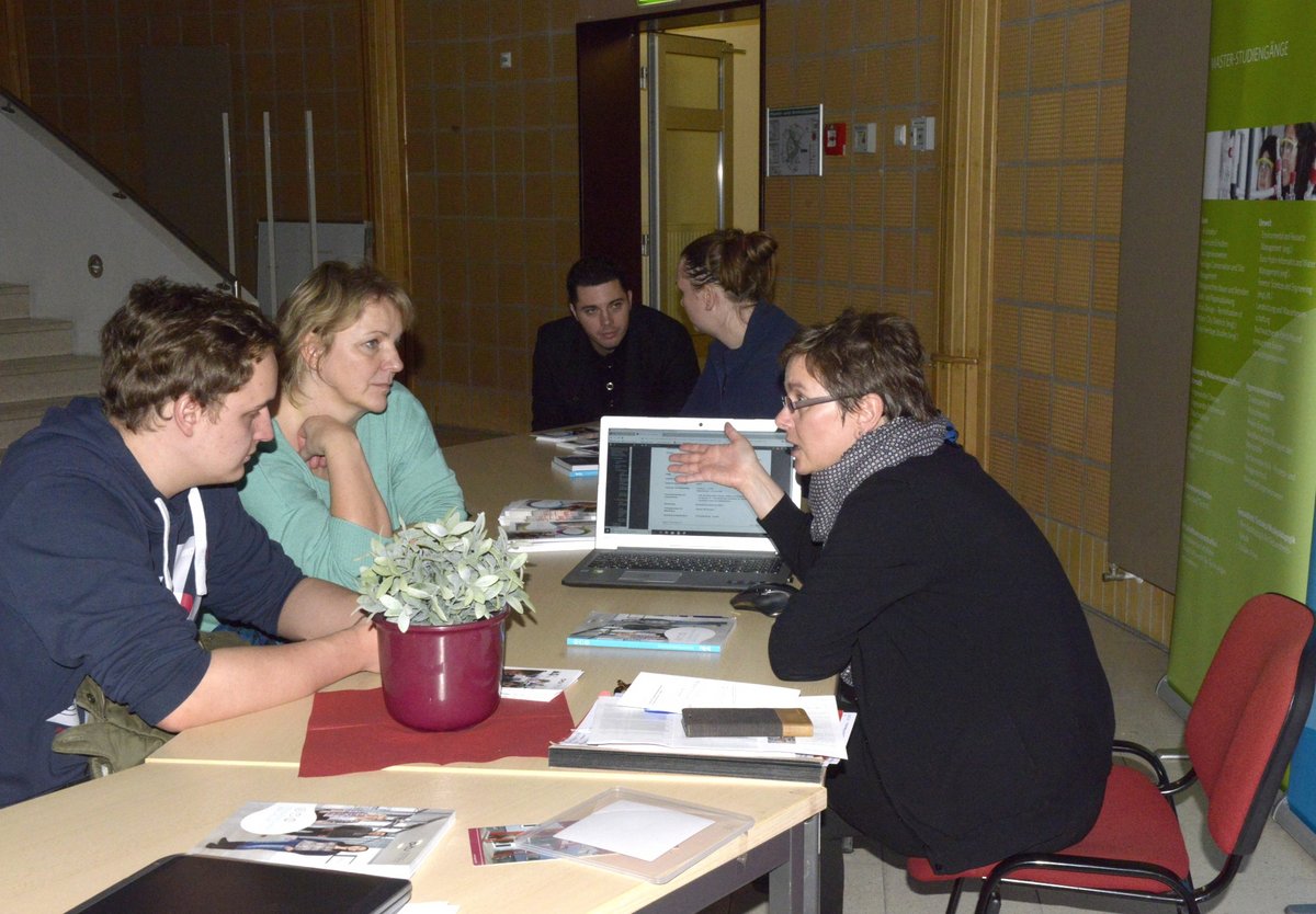 BTU-Studienberaterin Heike Postelt, an einem Tisch sizend, im Gespräch mit Besuchern des Studieninformationstages "Einblicke".