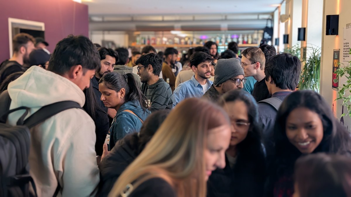 Viele Perosnen stehen ineiner Bar und unterhalten sich angeregt. 