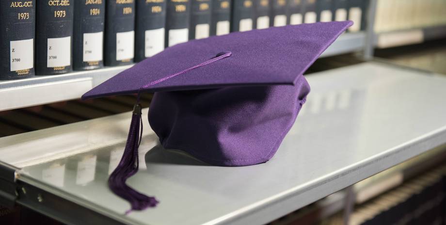 Alumnihut Ein Doktorandenhut liegt vor Büchern in der Bibliothek
