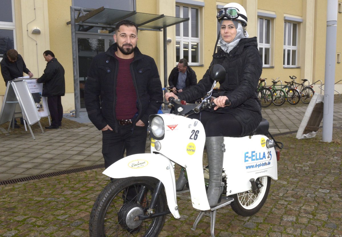 Faten Sarmini (sitzend) und Mohammad Suliamman (stehend) aus Syrien mit einem im Rahmen des Projektes „International“ auf Elektroantrieb umgerüsteten Mopeds, Typ "Schwalbe".