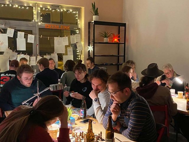 Blick in den Raum mit Menschen an Spieltischen