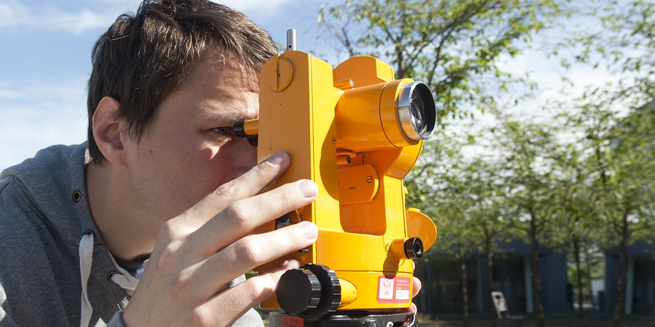 Student of civil engineering looks through a surveying instrument