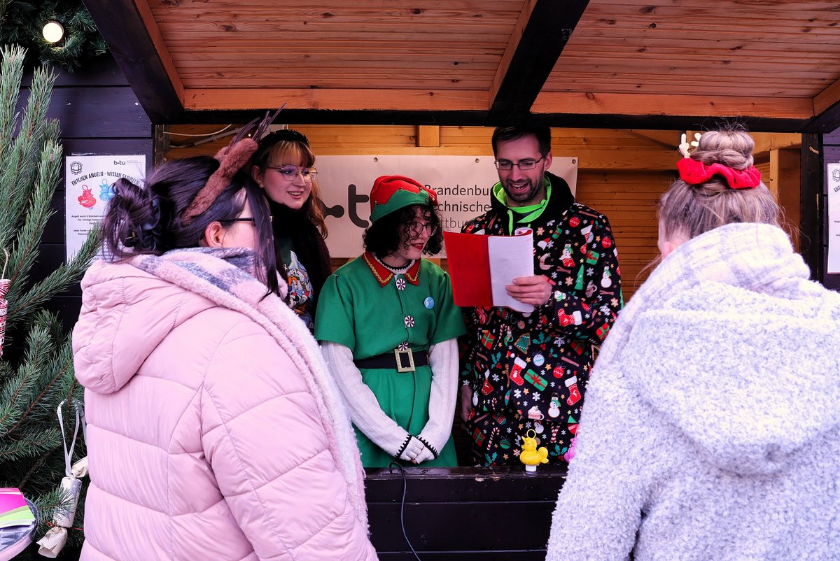 Students in a Christmas hut talk to visitors.