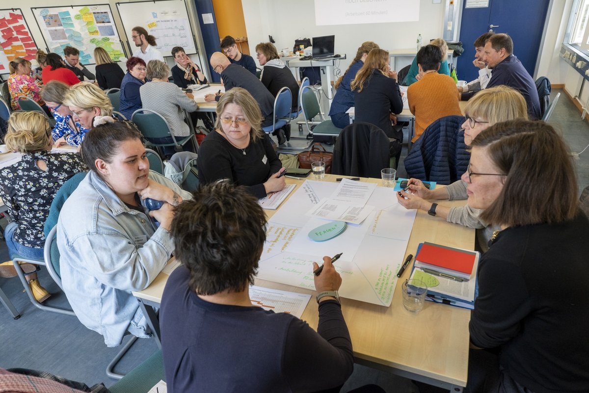 Participants of the 7th Senftenberg Workshop discussing at tables.