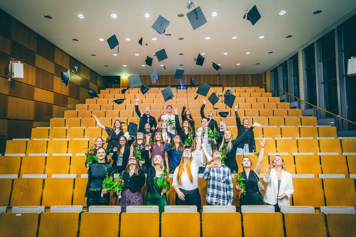 Graduierte werfen ihre Hüte hoch