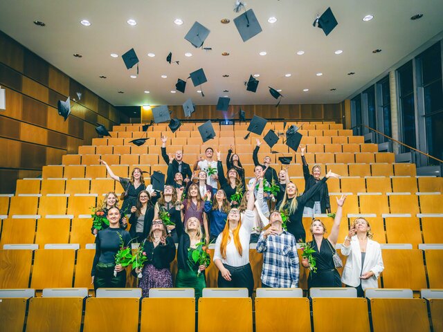 Graduierte werfen ihre Hüte hoch