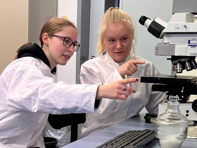 Die MINT-Frauen-Stipendiatinnen Ronja Tittel (links) und Nele Hoffmann an einem Mikroskop im Labor.