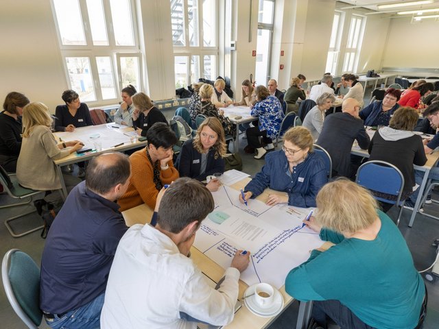 Participants of the 7th Senftenberg Workshop discussing at tables.