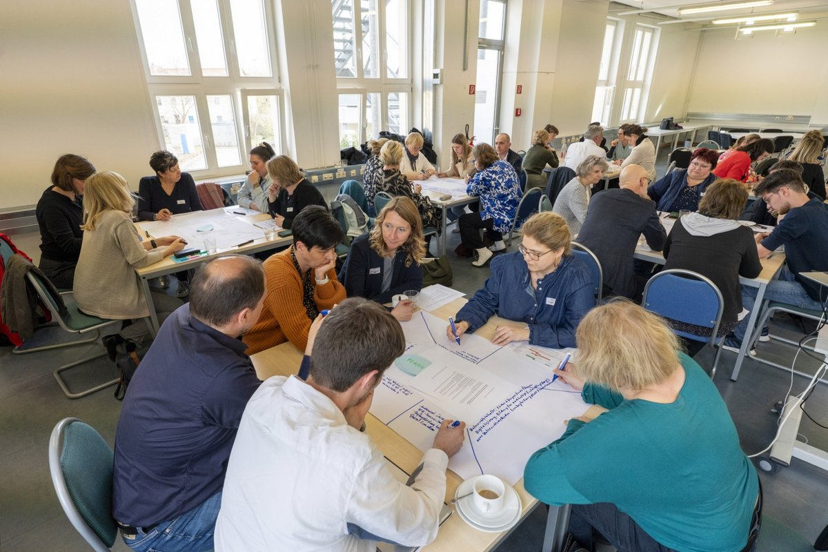 Participants of the 7th Senftenberg Workshop discussing at tables.