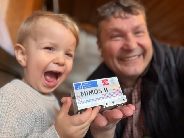 Prof. Franz Renz und ein kleines Kind präsentieren das miniaturisierte Mössbauer Spektrometer (MIMOS).              