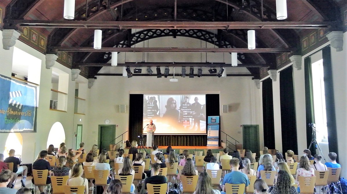 Schülerinnen und Schüler forlgen in der Aula des Sängestadtgymnasiums der Vorlesung von Prof. Jens Becker.
