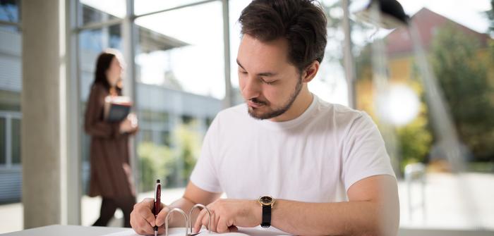 BWL-Studium Student mit Büchern vor Glasfasade