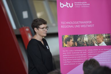 BTUTransferTag-Teilnehmerin im Seitenprofil neben einem Plakat über Technologietransfer