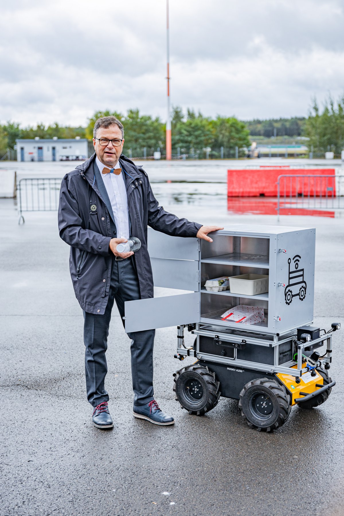 Prof. Dr.-Ing. Sylvio Simon steht neben einem Lieferroboter.