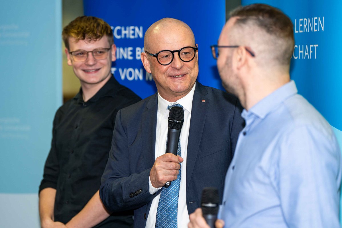 Martin Seiler with microphone in conversation with the two young men