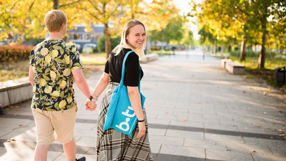 Studierende gehen eine Allee entlang