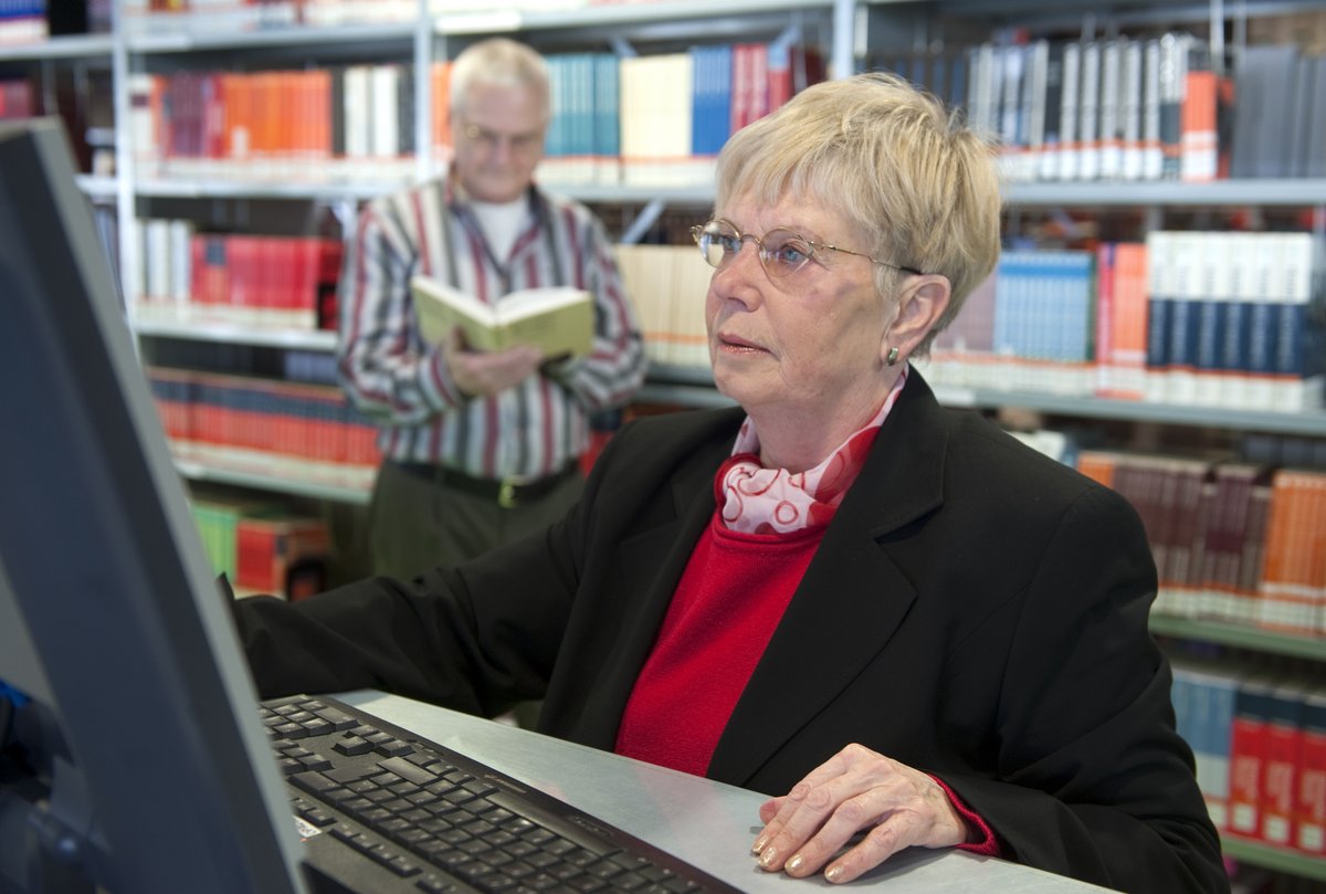 Eine Seniorstudentin in der Universitätsbibliothek am PC arbeitend.