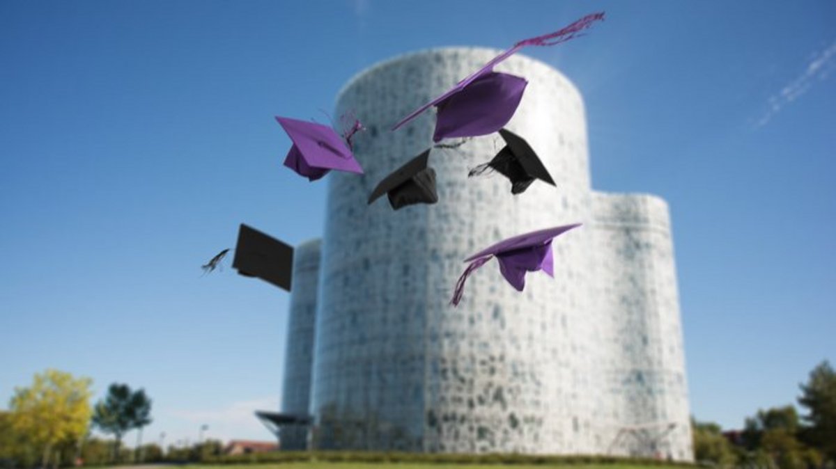 Symbolbild Alumni fliegende Doktorhüte vor dem IKMZ-Gebäude