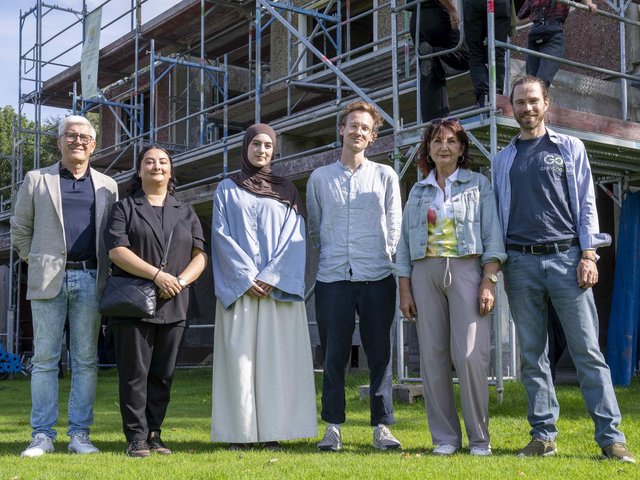 Prof. Dr.-Ing. Angelika Mettke mit ihrem Team beim Richtfest - vor dem Erweiterungsbau des Mehrzweckgebäudes in Kolkwitz stehend.
