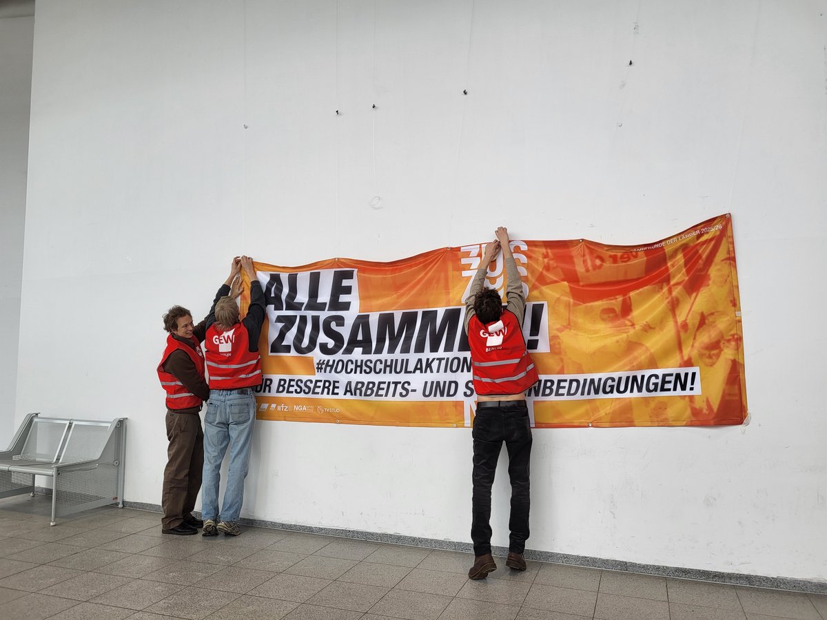 Drei Gewerkschafter bringen ein Banner an.