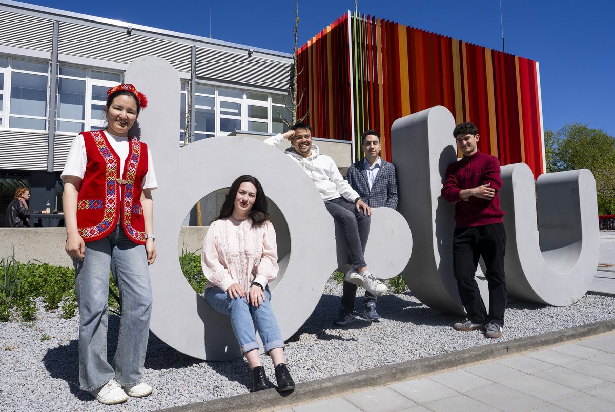Vier Studierende an dem fast zwei Meter hohen plastischen Schriftzug b-tu.gübergroßen Logo der BTU