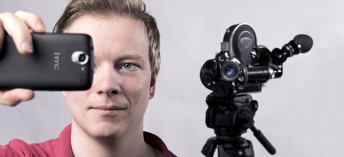 Werbebild für den Bachelor Kultur und Technik: ein junger Mann filmt mit dem Smartphone, im Hintergrund steht eine Videokamera