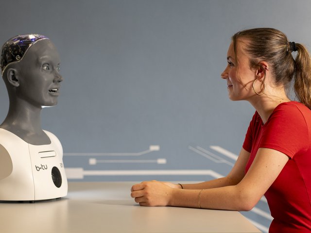 Mädchen im Gesprräch mit einem humanoiden Roboter.