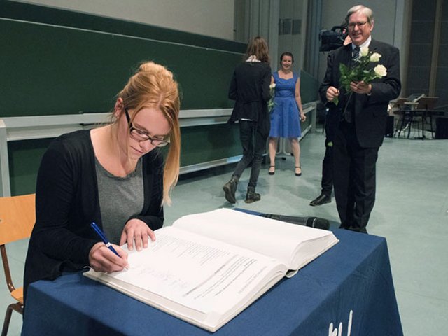Eine Studentin trägt sich in das Immatrikulationsbuch der BTU ein.