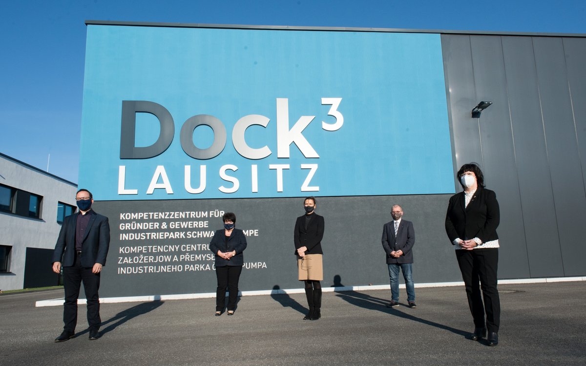 Die Kooperationspartner*innen stehen in größeren Abständen vor dem Gebäude des „Dock3 Lausitz“.