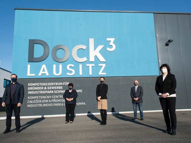 Die Kooperationspartner*innen stehen in größeren Abständen vor dem Gebäude des „Dock3 Lausitz“.