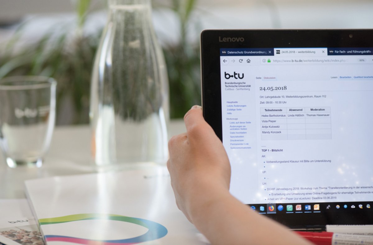 Das Foto zeigt enen Laptop und eine Karaffe mit Wasser.