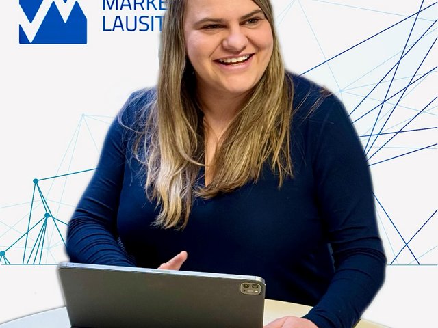 Maria Erdmann sits in front of the marketing logo