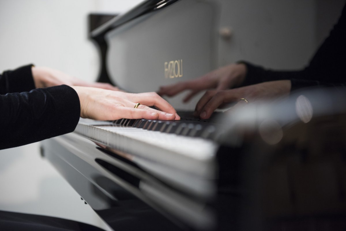 Das Foto zeigt eine Klaviertastatur und spielende Hände.