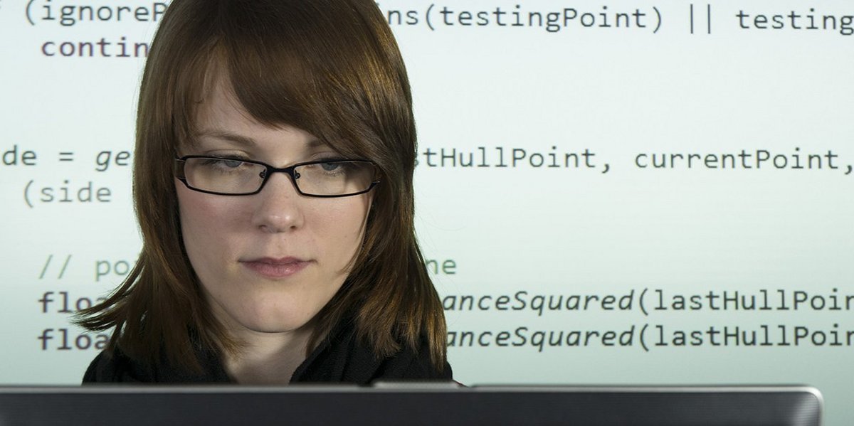 Studentin im Bachelor Informatik am Laptop, im Hintergrund Programmcode