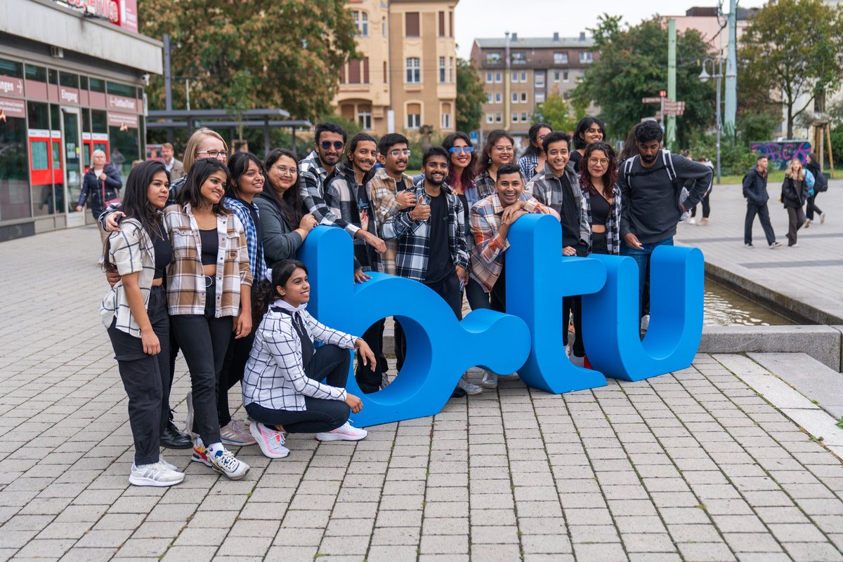 Studierende positionieren sich vor einem großen blauen BTU-Logo