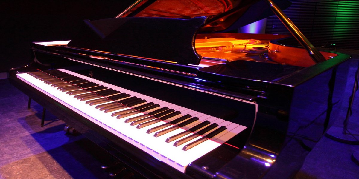 A concert grand piano illuminated in different colours - symbolic image for the bachelors programme in instrumental and vocal performance and teaching