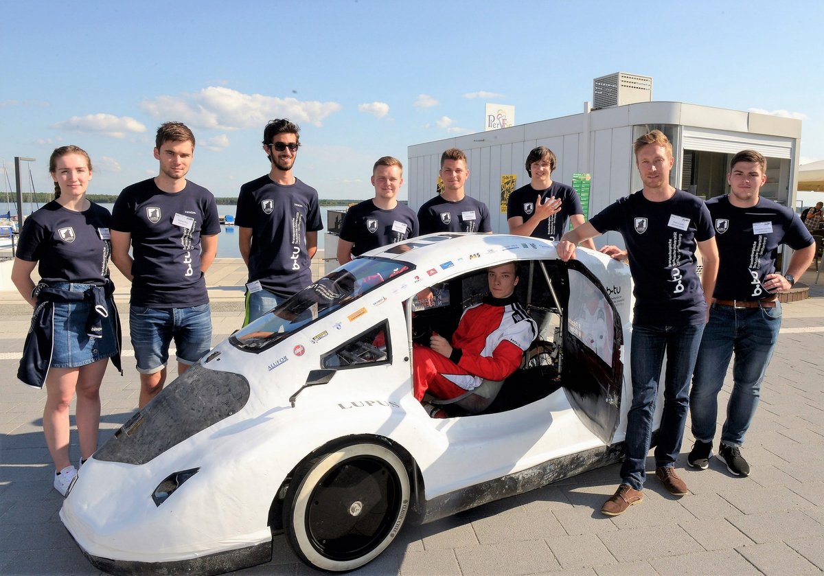 Gruppenfoto des studentischen Teams Lausitz Dynamics mit seienm Energiesparmobil Lupus - aufgenommen an Senftenberger Stadthafen. 