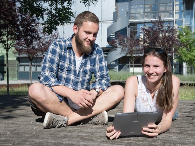 Studierende mit Laptop vor dem Lehrgebäude 2A
