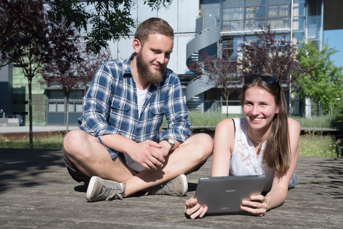 Studierende mit Laptop vor dem Lehrgebäude 2A